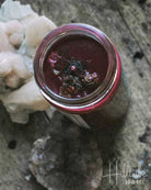 Jar with a dark liquid on a textured surface, possibly stone or concrete.
