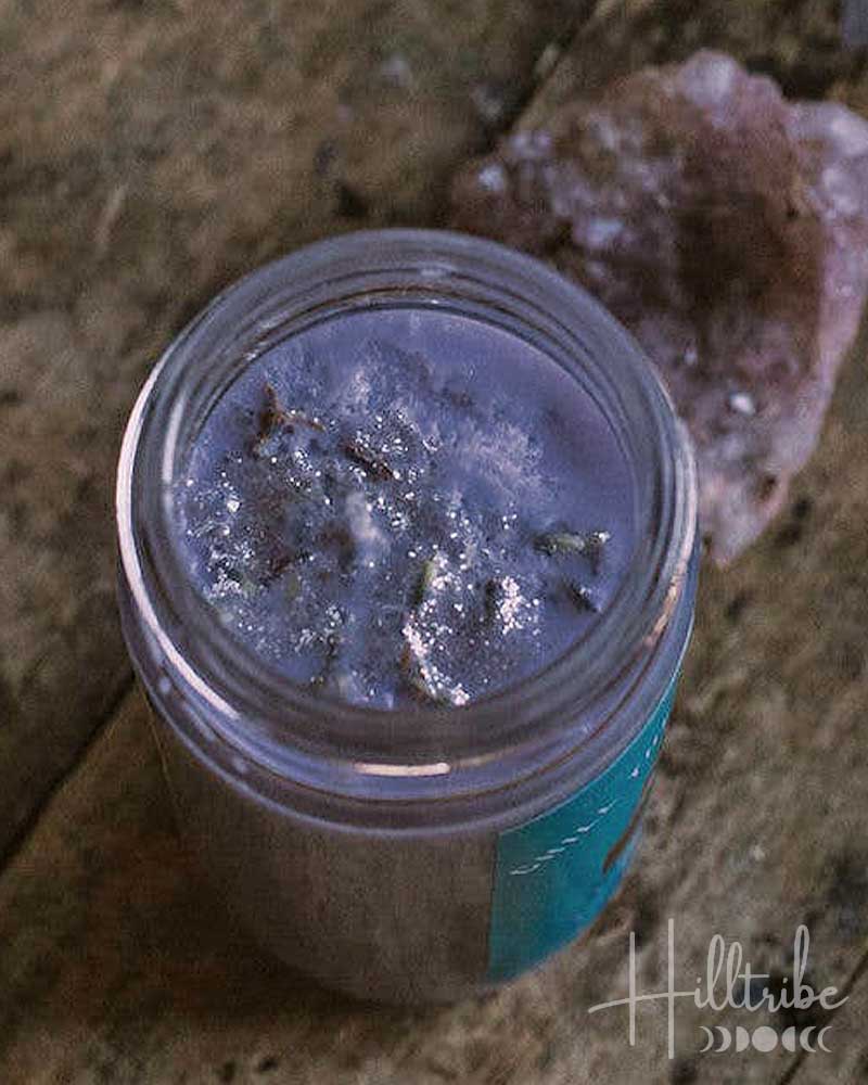 Jar of purple powder with a blue label on a rustic wooden surface, featuring the brand 'Hilltribe'.
