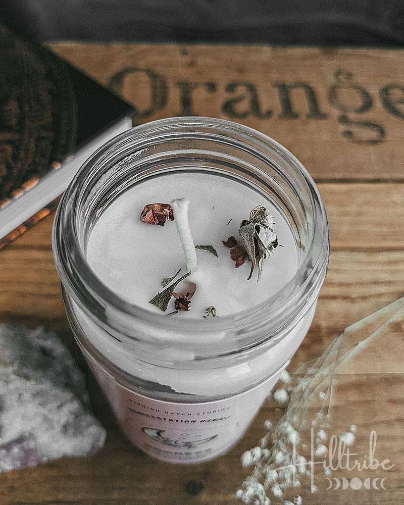Candle in a glass jar with dried herbs on a wooden surface, featuring the brand 'Fulltribe'.