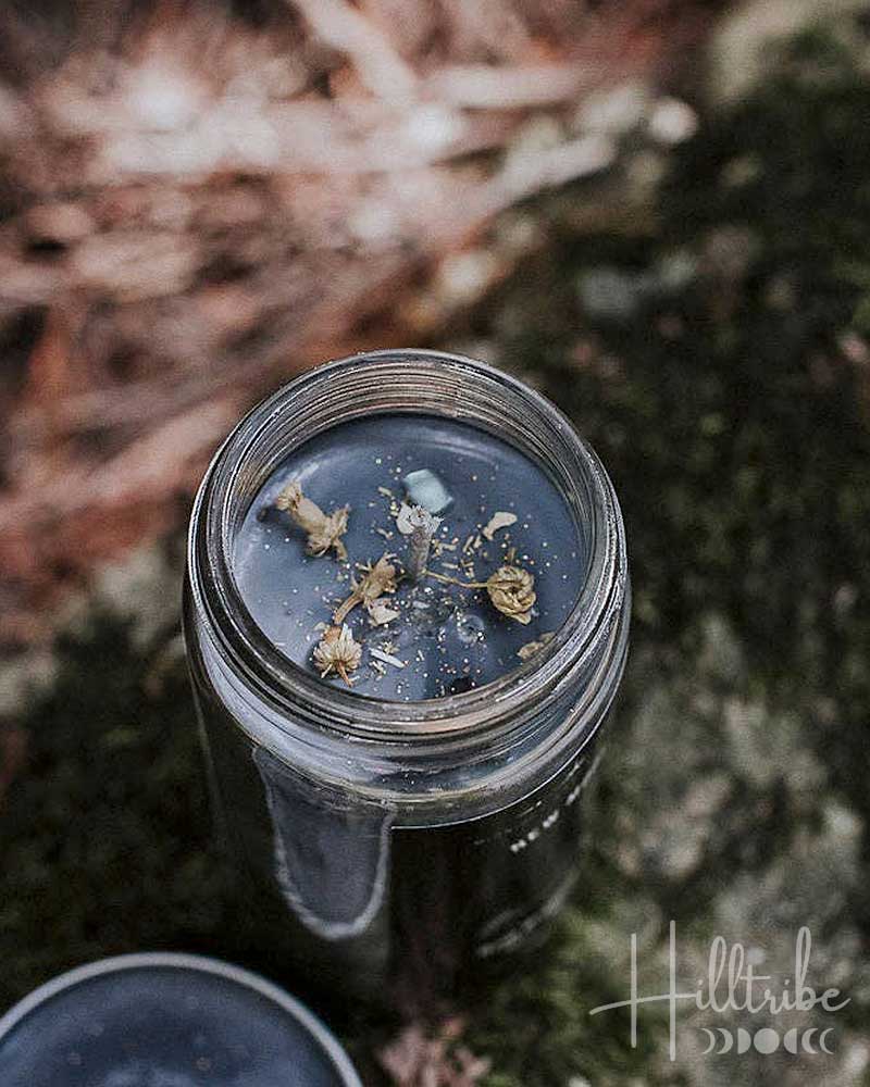 Glass jar with dried herbs on a natural background, featuring the brand 'Hilltribe'.