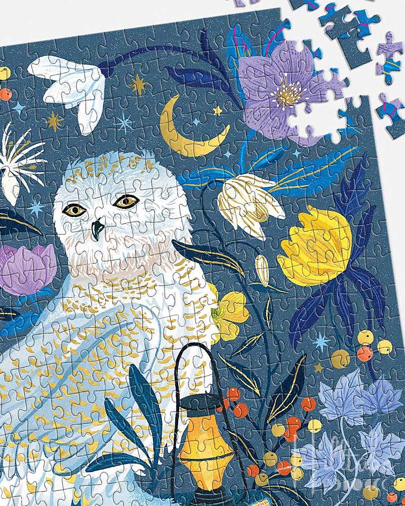 Jigsaw puzzle with a snowy owl and floral design on a blue background