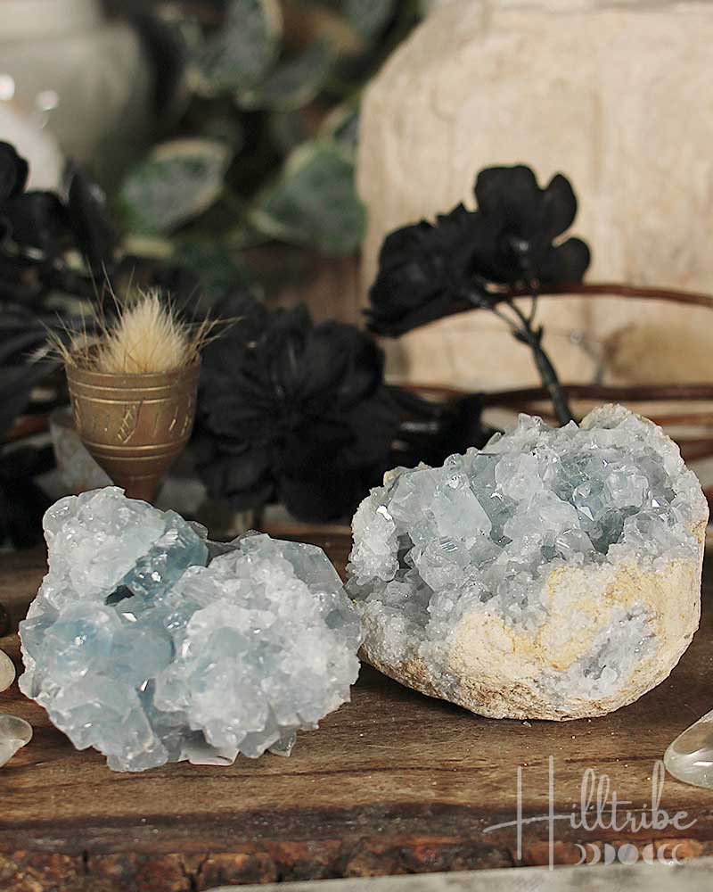Two crystal formations on a wooden surface with blurred background
