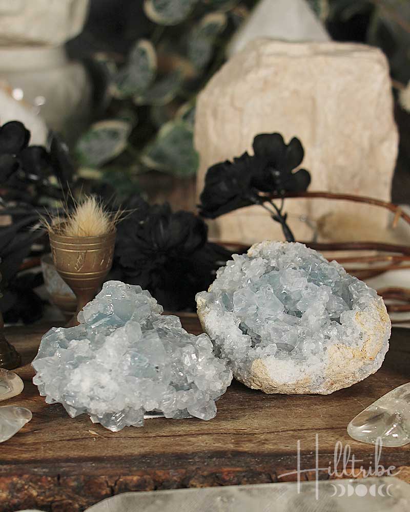 Two large crystal formations on a wooden surface with blurred background