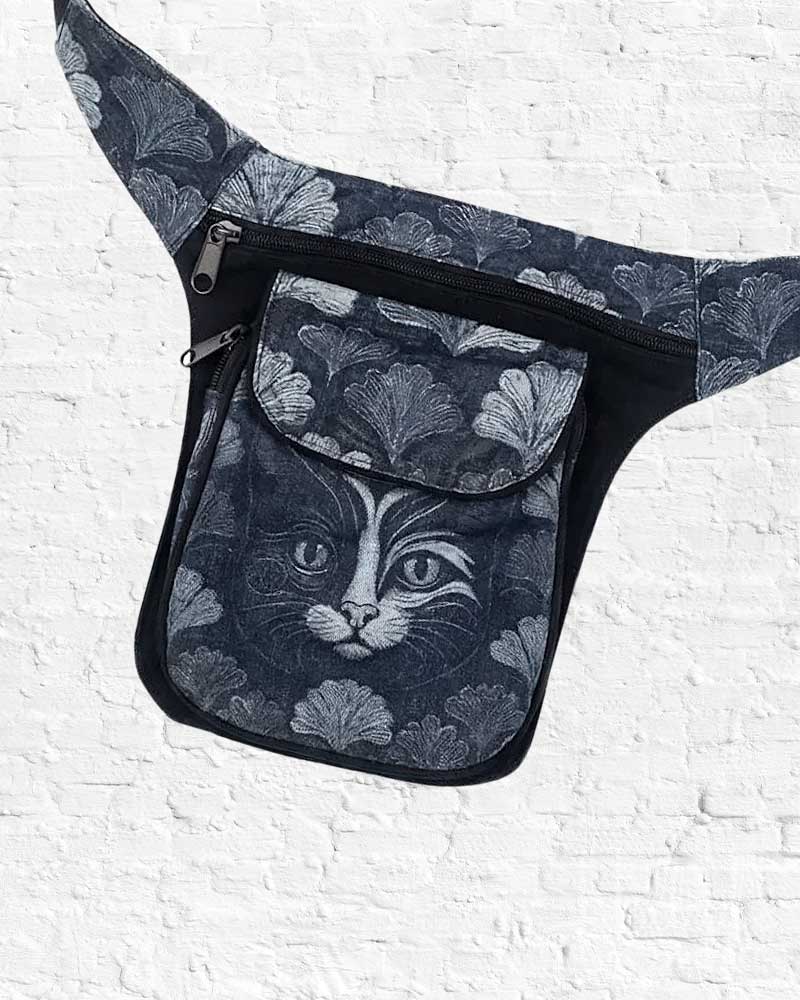 Floral-patterned sling bag with a cat design on a white brick wall background