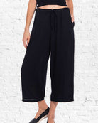 Person wearing black wide-leg pants against a white brick wall.