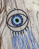 Dreamcatcher with blue and white feathers on a wooden surface