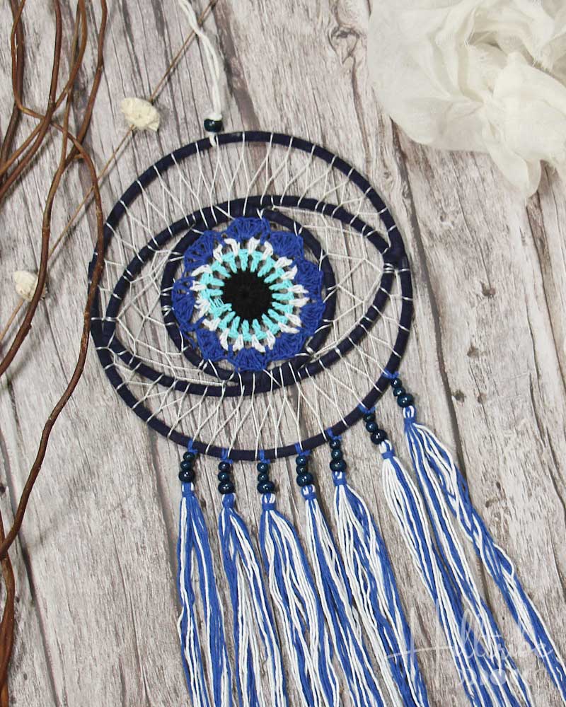 Dreamcatcher with blue and white feathers on a wooden surface