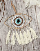 Dreamcatcher with eye design and tassels on a wooden surface