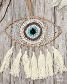 Decorative eye-shaped dreamcatcher with tassels on a wooden background