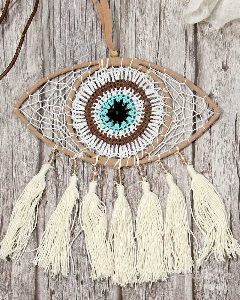 Decorative eye-shaped dreamcatcher with tassels on a wooden background