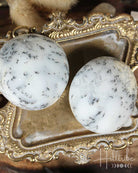 Two Dendritic Agate stones on a decorative gold surface with 'Hilltribe' branding.
