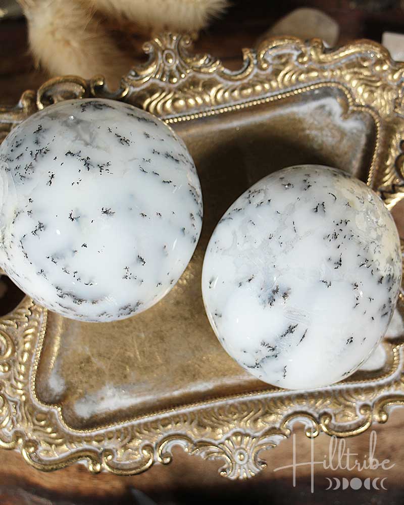 Two Dendritic Agate stones on a decorative gold surface with 'Hilltribe' branding.