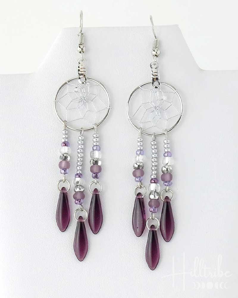 Pair of earrings with purple teardrop beads on a white background