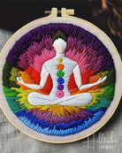 Embroidery hoop with a colorful depiction of a meditating figure and chakra symbols.