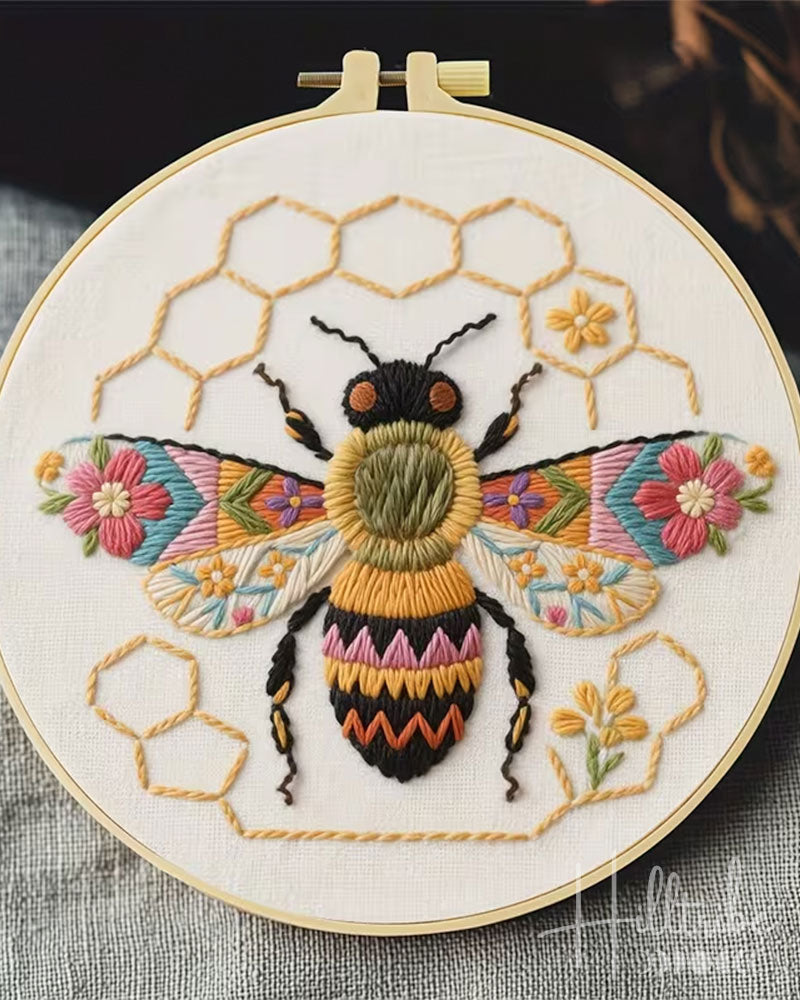 Embroidery hoop with a colorful bee and honeycomb design.