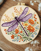 Embroidery hoop with a dragonfly and floral design on a wooden surface