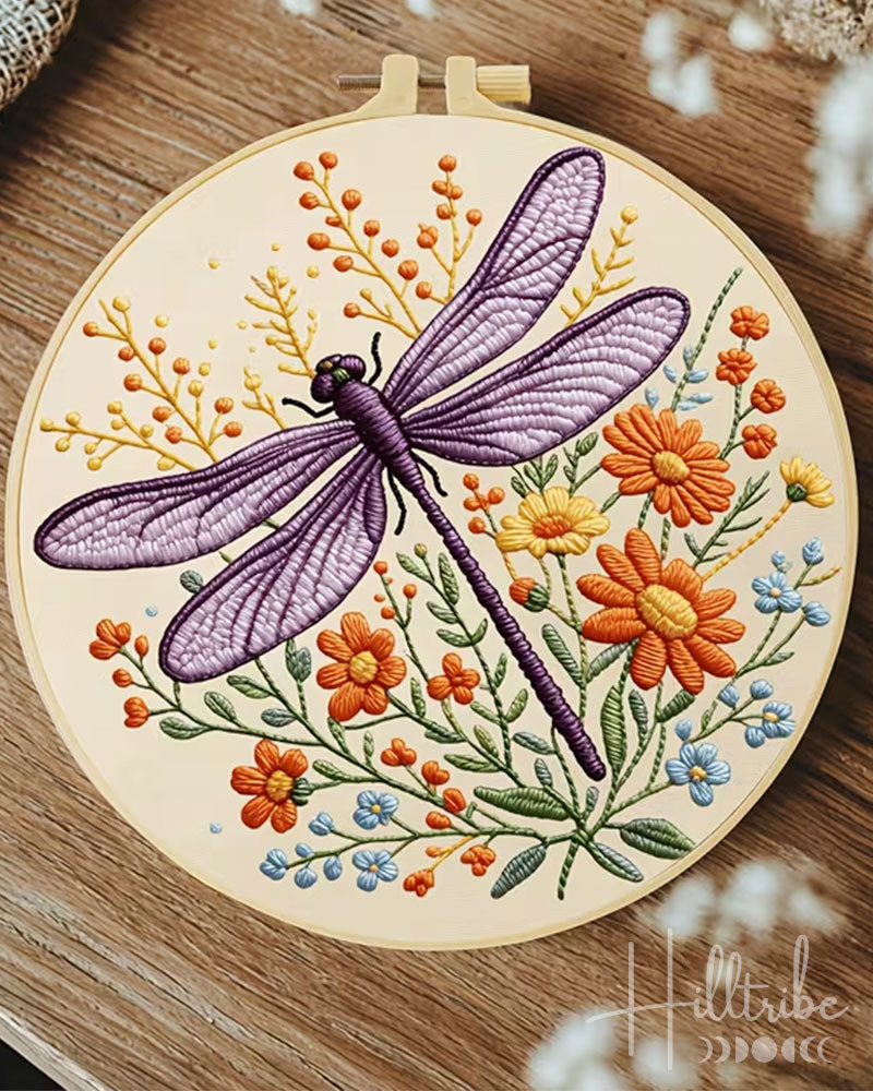 Embroidery hoop with a dragonfly and floral design on a wooden surface