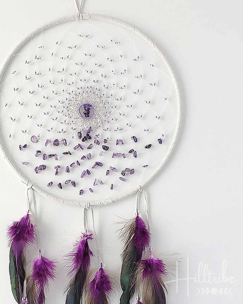 Dreamcatcher with purple stones and feathers on a white background