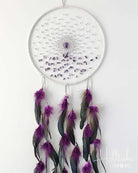 White dreamcatcher with purple feathers on a white background