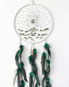 White dreamcatcher with green feathers on a white background