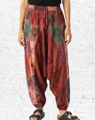 Person wearing patterned harem pants against a white brick wall.