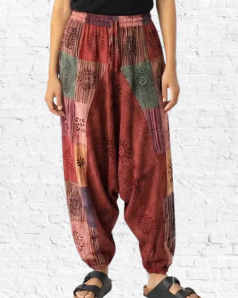 Person wearing patterned harem pants against a white brick wall.