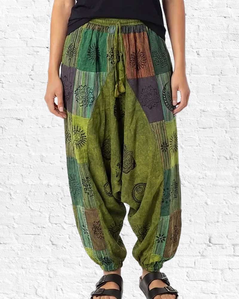 Green patchwork harem pants worn by a person on a white brick wall background