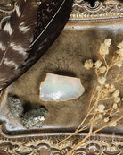 Opal stone with feathers and dried flowers on a decorative surface