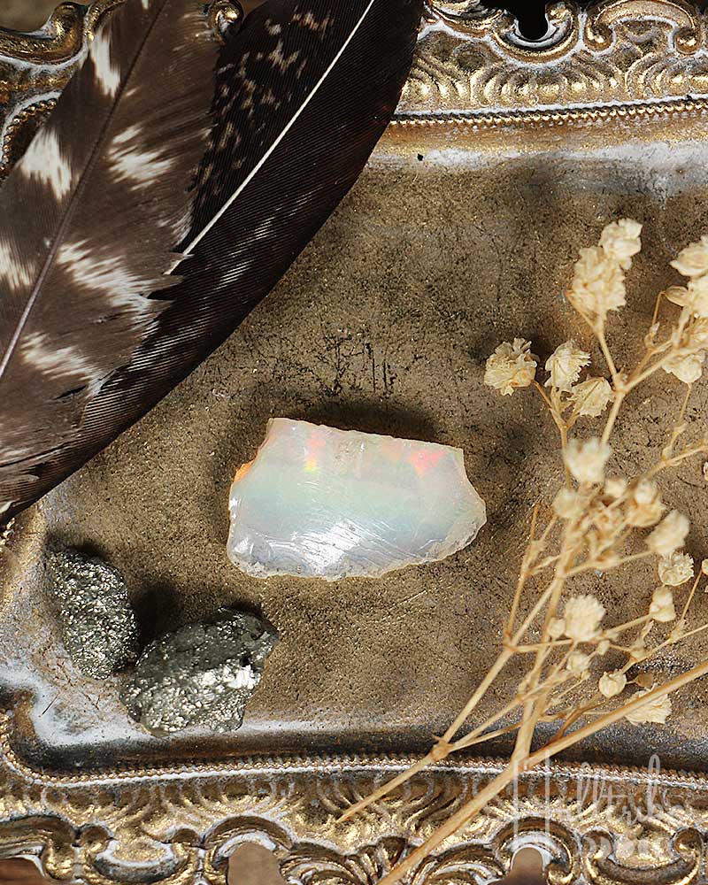 Opal stone with feathers and dried flowers on a decorative surface