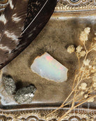 Opal stone with feathers and dried flowers on a textured surface