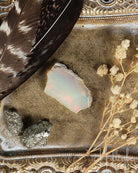 Opal stone with feather and dried flowers on an ornate surface