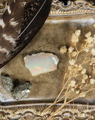 Opal stone with feathers and flowers on a decorative surface