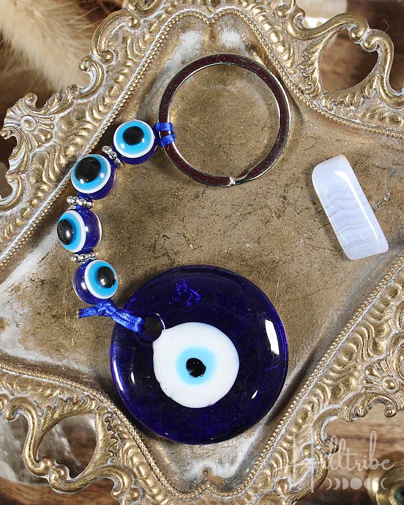 Blue evil eye charm on a decorative metal surface