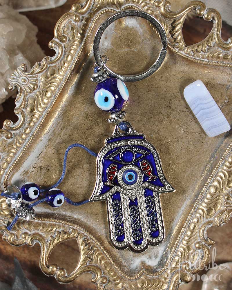 Decorative keychain with Hamsa hand and evil eye charms on a decorative surface.