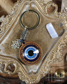 Keychain with blue evil eye design and hamsa hand charm on an ornate surface