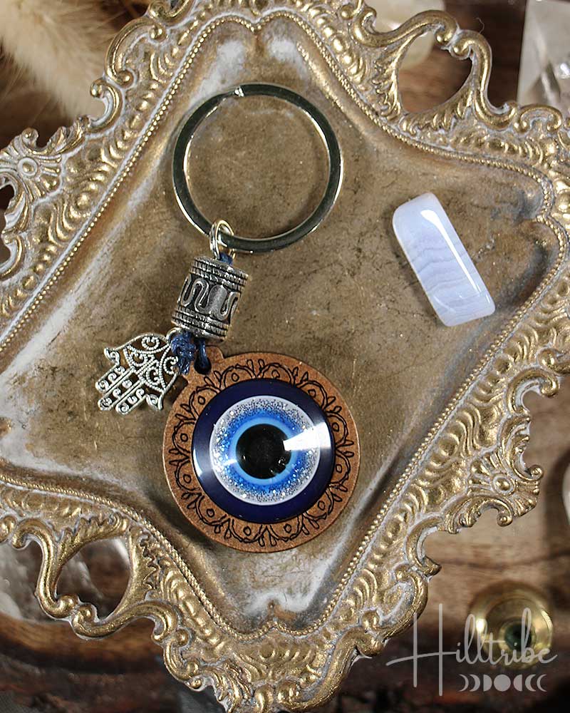 Keychain with blue evil eye design and hamsa hand charm on an ornate surface