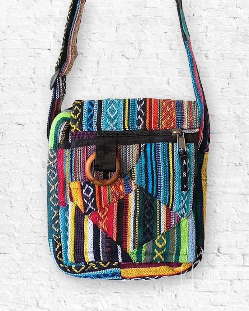 Colorful patterned crossbody bag on a white brick wall background