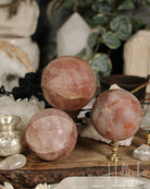 Three Fire Quartz crystal spheres on a wooden surface with blurred background