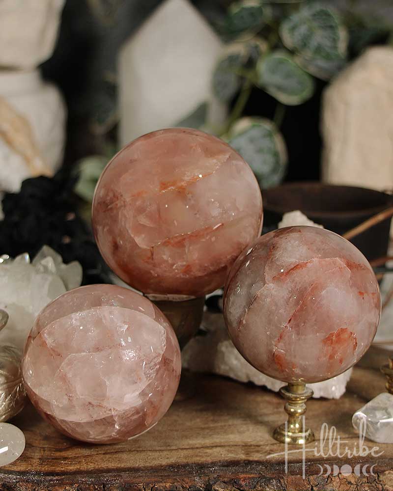 Three Fire Quartz crystal spheres on a wooden surface with blurred background