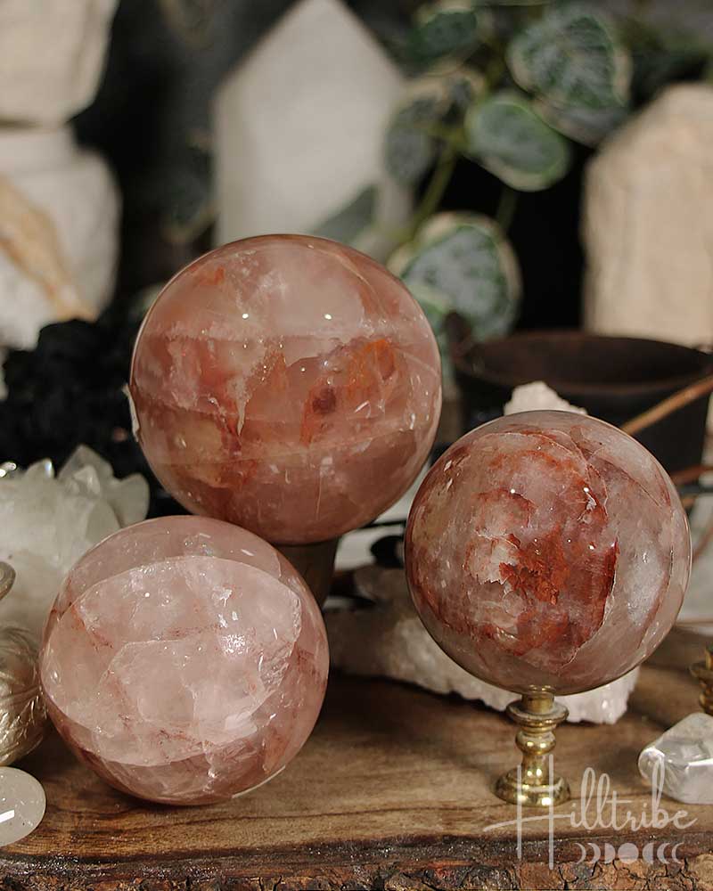 Three Fire Quartz crystal spheres on a wooden surface with blurred background