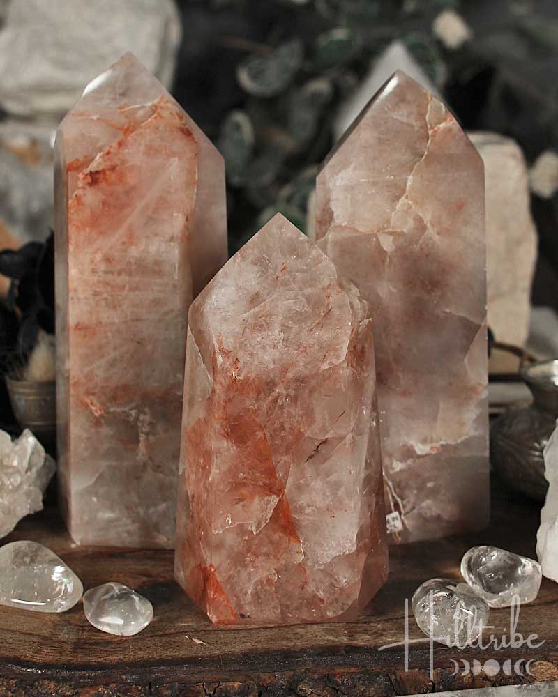 Three Fire Quartz Polished crystal Points on a wooden surface with blurred natural background