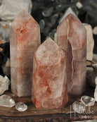 Three Fire Quartz Polished crystal Points on a wooden surface with blurred natural background