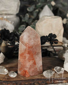 Fire Quartz Polished crystal Point on a wooden surface with blurred natural background