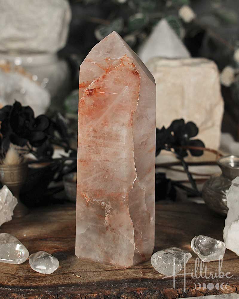 Fire Quartz Polished crystal Point on a wooden surface with blurred natural background