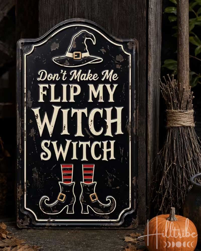 A decorative Halloween sign with the text 'Don't Make Me Flip My Witch Switch' in distressed cream lettering on a black background, featuring a witch hat and boots illustration. The sign is styled outdoors on a stone surface with autumn leaves, a small white pumpkin, an orange pumpkin, a lantern, a broom, and a black pot.
