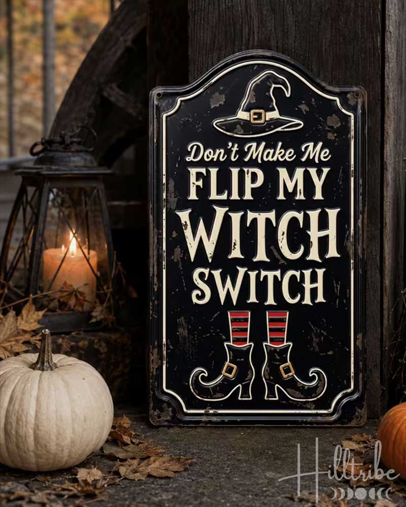 A decorative Halloween sign with the text 'Don't Make Me Flip My Witch Switch' in distressed cream lettering on a black background, featuring a witch hat and boots illustration. The sign is styled outdoors on a stone surface with autumn leaves, a small white pumpkin, an orange pumpkin, a lantern, a broom, and a black pot.