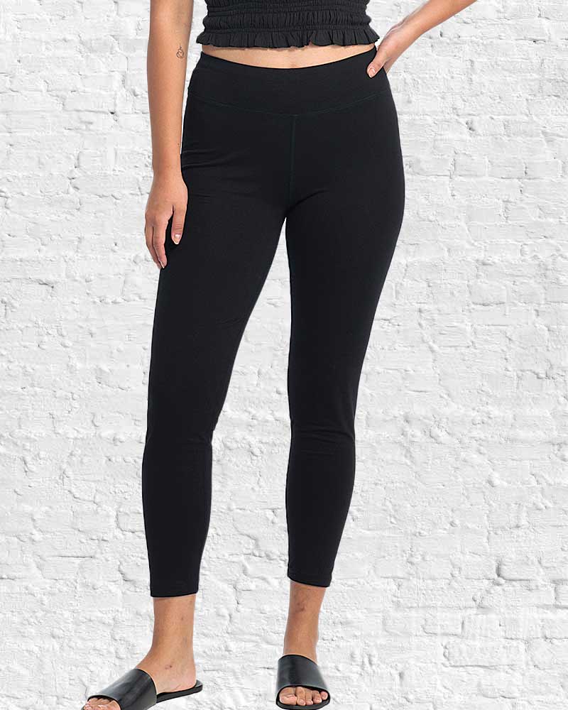 Person wearing black leggings against a white brick wall