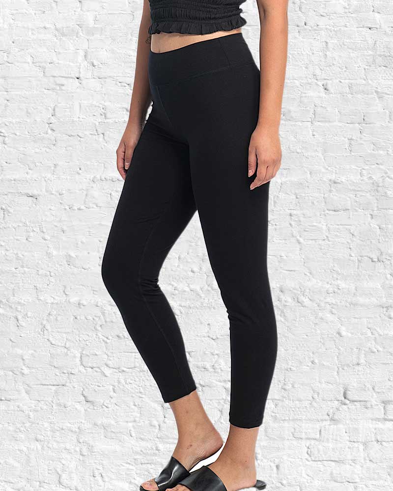 Person wearing black leggings against a white brick wall.