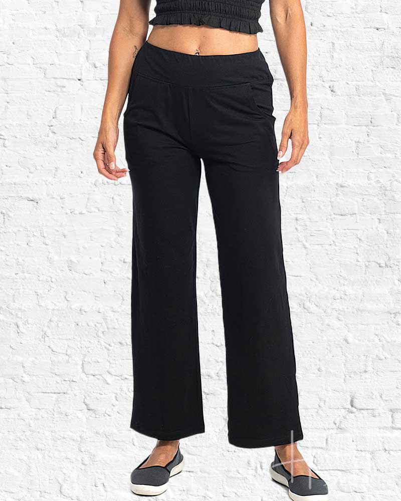 Person wearing black wide-leg pants against a white brick wall.