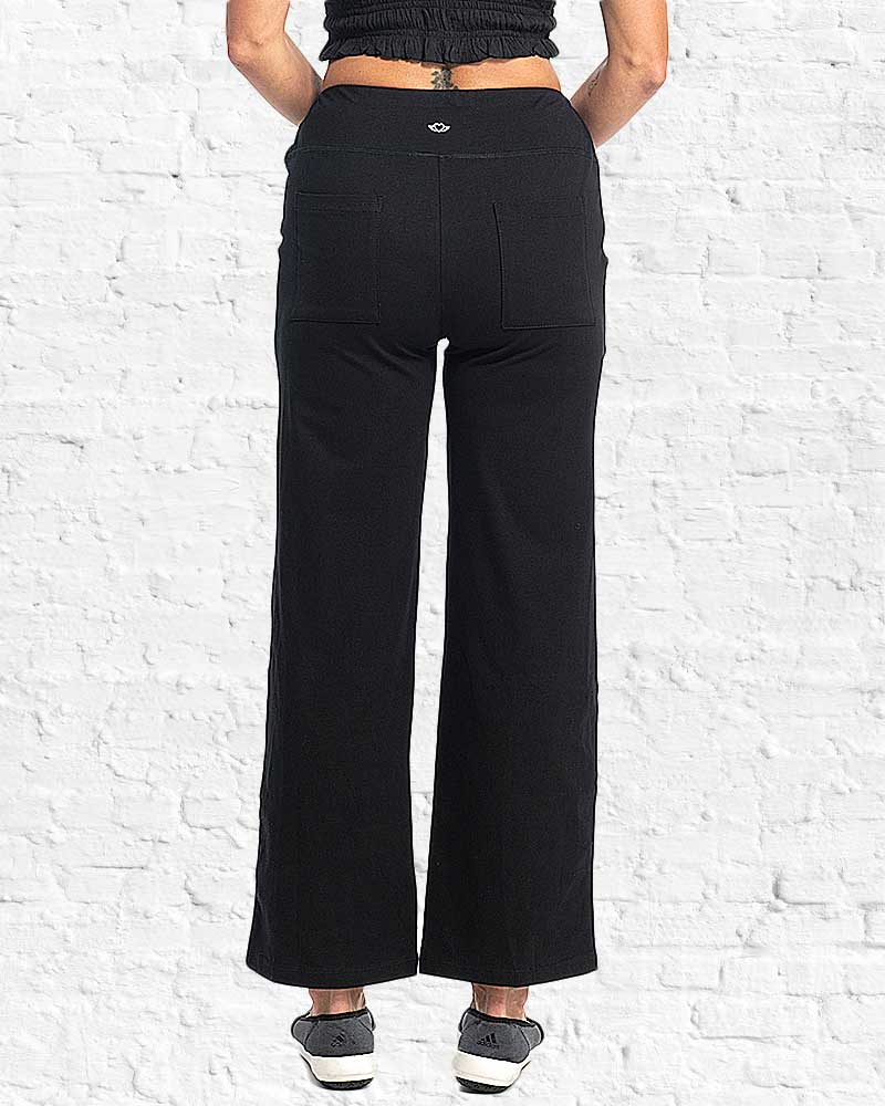 Person wearing black wide-leg pants against a white brick wall.